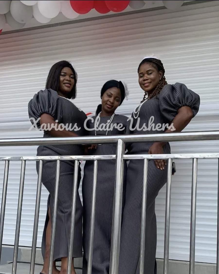 Three Xavious Claire hostesses in matching charcoal uniforms on a balcony above an event
