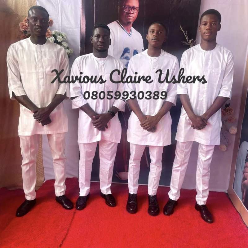 Four Xavious Claire male ushers in white kaftans lined up at the entrance to an event